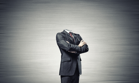 Headless businessman with arms crossed on chest in black suitの写真素材