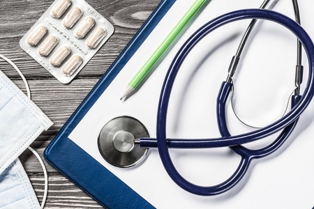 Doctors wooden table with tablet stethoscope and other stuffの写真素材