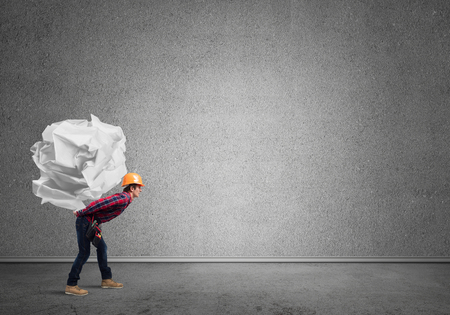 Builder man carrying paper ball on his backの写真素材