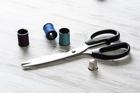 Old scissors bobbins threads and tape on wooden table