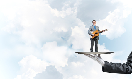 Hand of waiter presenting on tray man playing guitarの写真素材