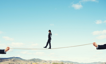 Business concept of risk support and assistance with man balancing on ropeの写真素材