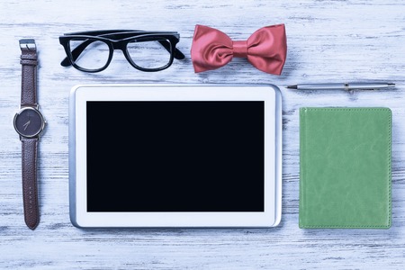 Gentleman kit of tablet watch glasses bow tie and notebook on woの写真素材