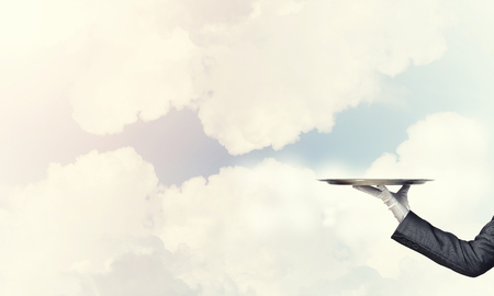 Waiter holding empty silver platter ready for product or item placementの写真素材