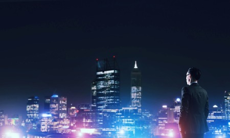 Businessman viewing night glowing cityの写真素材