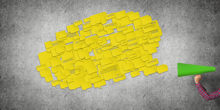 Hand of man holding red paper trumpet and speech cloud coming outの写真素材