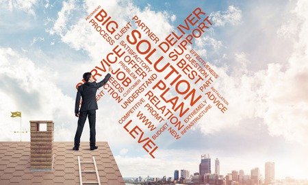 Young businessman standing on house roof and writing leadershipの写真素材