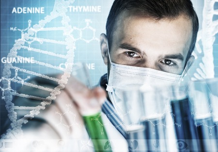 Young scientist mixing reagents in glass flask in clinical laboratoryの写真素材