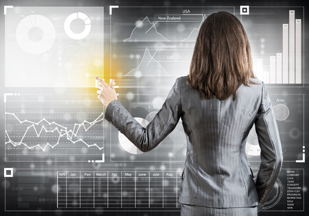 Businesswoman standing with back and pressing icon on media screenの写真素材