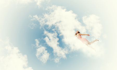 Young woman flying high in blue skyの写真素材