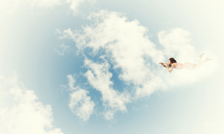 Young pretty woman flying in sky and playing fifeの写真素材