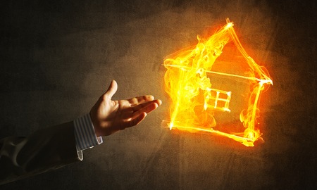 Fire house glowing icon and hand on dark backgroundの写真素材