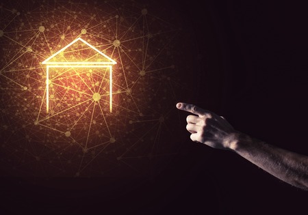 Hand of man touching with finger glowing home icon or symbolの写真素材