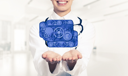 Close of woman doctor holding in palms cloud of gear mechanismの写真素材