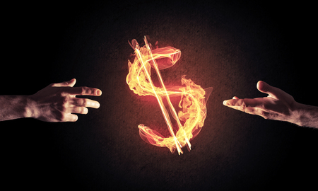 Close of businessman hands pointing at fire glowing dollar signの写真素材