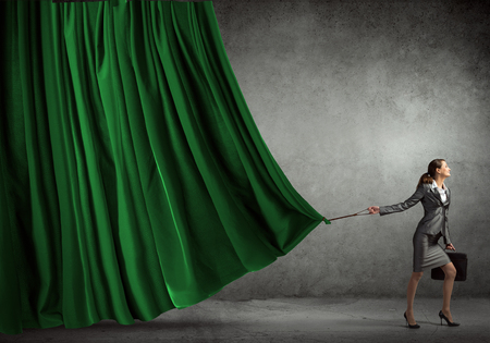 Young businesswoman pulling curtain with lead. Place for textの写真素材