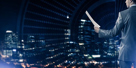 Rear view of businessman against virtual panel interface holding papers in handの写真素材