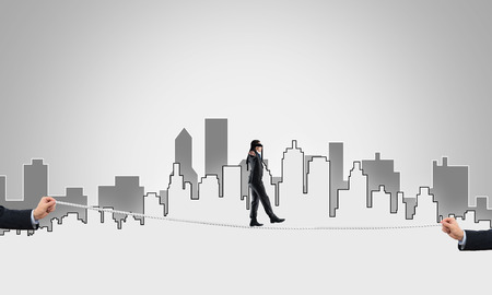 Businessman with blindfolder on eyes walking on ropeの写真素材