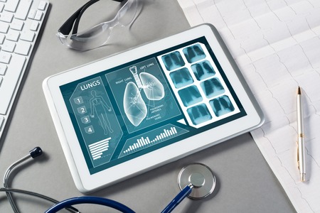 White tablet pc and doctor tools on gray surfaceの写真素材