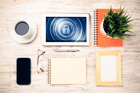 Business workplace with office stuff and tablet with padlock icons on screenの写真素材