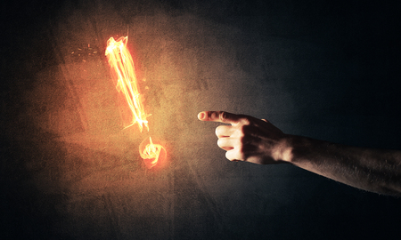 Hands reaching each other and fire glowing exclamation markの写真素材