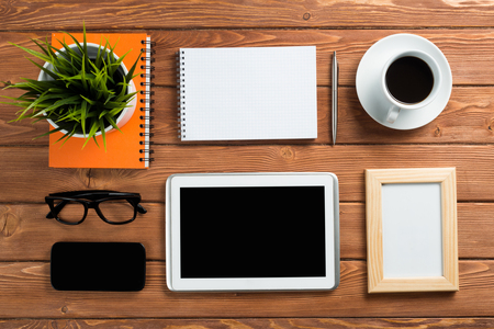 Still life photo of tablet notepad coffee glasses and other stuff on wooden tableの写真素材