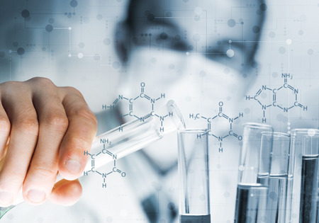 Young scientist mixing reagents in glass flask in clinical laboratoryの写真素材