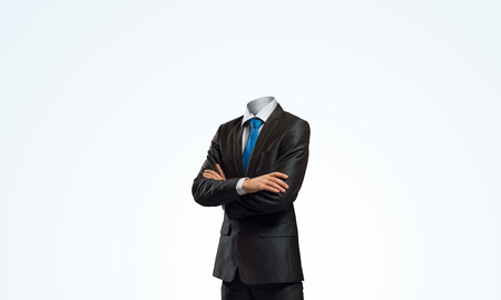 Headless businessman with arms crossed on chest in black suitの写真素材