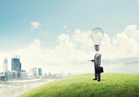 Businessman outdoor with suitcase and bulb instead of headの写真素材
