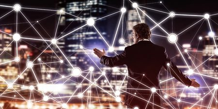 Back view of businessman against night cityscape working with social connection media conceptの写真素材