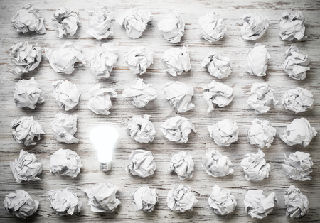 Many balls of crumpled paper and glowing light bulbの写真素材
