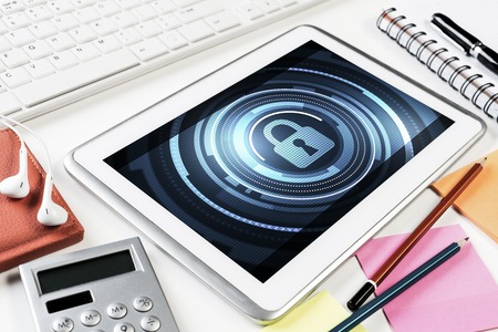 Business workplace with office stuff and tablet with padlock icon on screenの写真素材