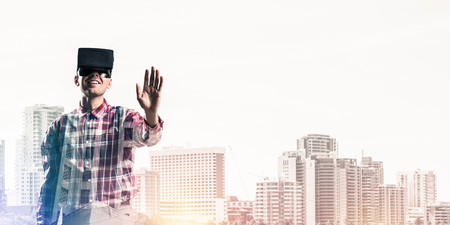 Young man with virtual reality headset or 3d glasses over cityscape backgroundの写真素材