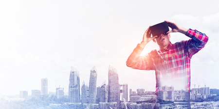 Young man with virtual reality headset or 3d glasses over cityscape backgroundの写真素材