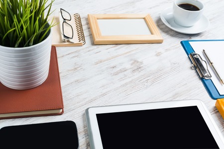 Still life photo of tablet notepad coffee glasses on wooden tableの写真素材