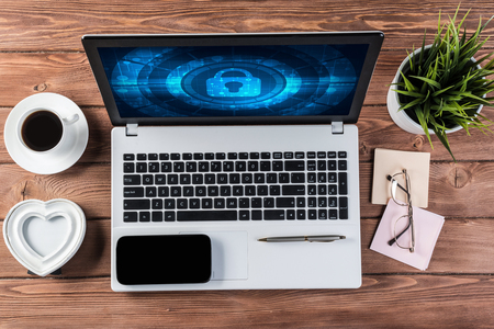 Business workplace with office stuff and laptop with padlock icons on screenの写真素材