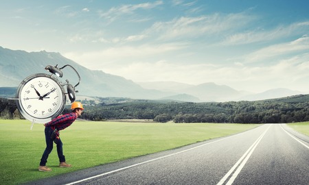 Builder man in helmet carrying alarm clock on back