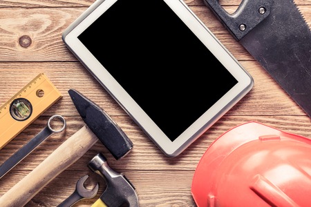 Variety of tools of builder and tablet pc on wooden texture tableの写真素材