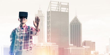 Young man with virtual reality headset or 3d glasses over cityscape background