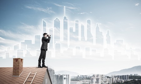 Young businessman viewing cityscape in his binoculars Mixed mediaの写真素材