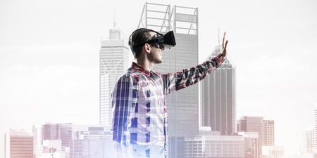 Young man with virtual reality headset or 3d glasses over cityscape background