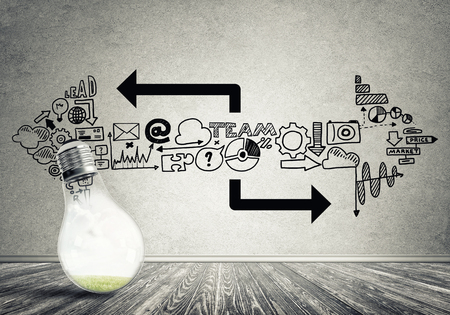 Glass glowing light bulb and business sketched ideas on wallの写真素材