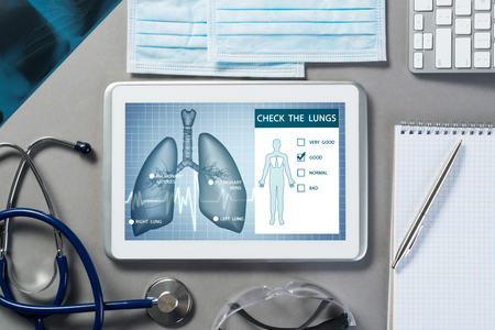 White tablet pc and doctor tools on gray surfaceの写真素材