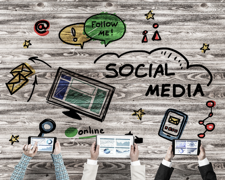 Group of three people with devices in hands working together as symbol of networking and communicationの写真素材