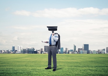 Elegant businessman outdoors with papers in hands and camera instead of headの写真素材