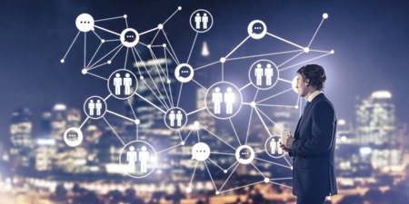Thoughtful businessman against night cityscape working with social connection media conceptの写真素材