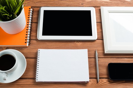 Still life photo of tablet notepad coffee glasses and other stuff on wooden tableの写真素材