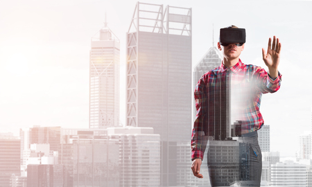 Young man with virtual reality headset or 3d glasses over cityscape backgroundの写真素材