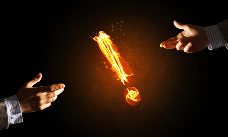 Hands reaching each other and fire glowing exclamation markの写真素材