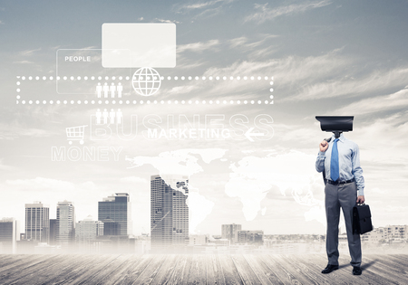 Elegant businessman outdoors holding jacket on shoulder and camera instead of his headの写真素材